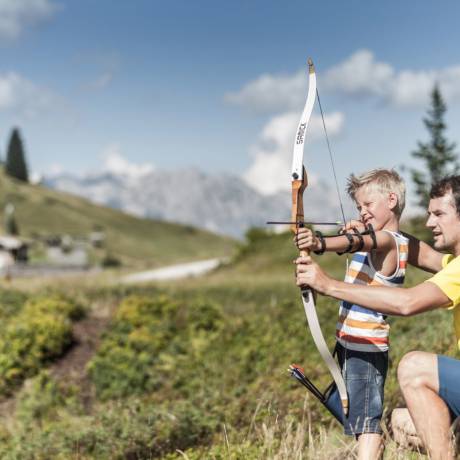 Vater zeigt Sohn wie Bogenschiessen geht in der Natur