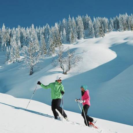 Paar beim Schneeschuhwandern in der verschneiten Winterlandschaft in den Bergen im Salzburger Land