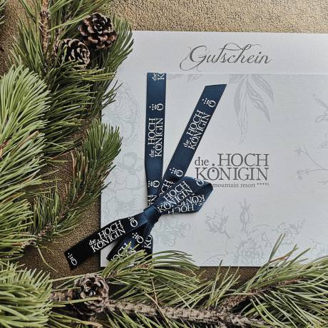 Voucher from Hotel die HOCHKÖNIGIN on a golden table with fir branches