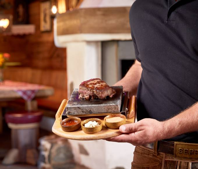 Kellner zeigt Steak mit Saucenvariation