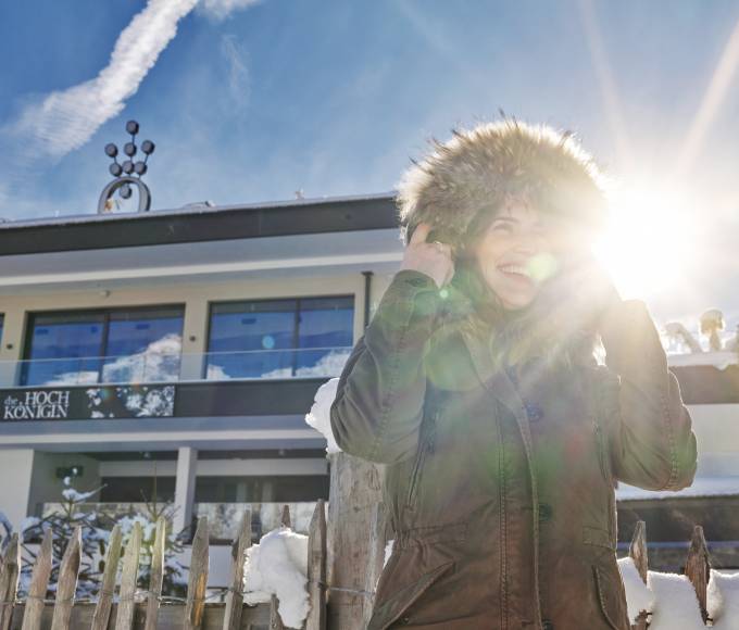 Frau in Winterjacke steht vor dem Wellnesshotel die Hochkönigin in Österreich