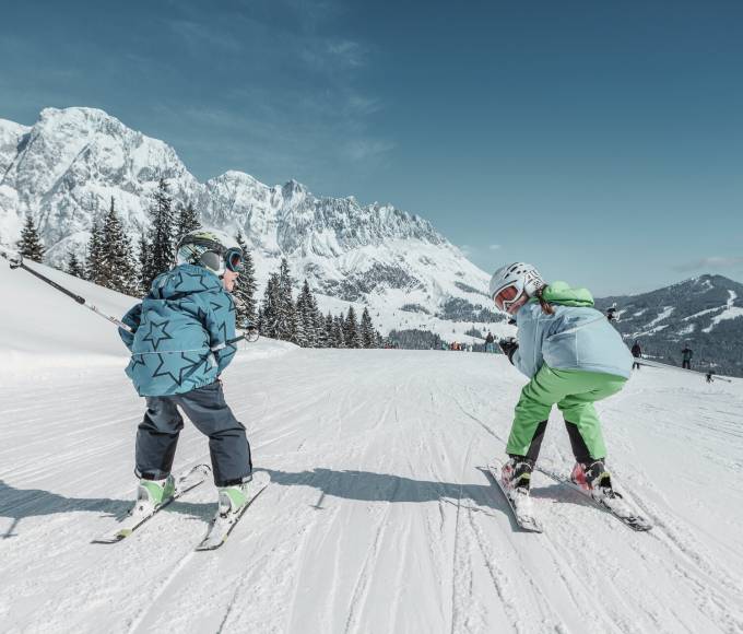 Kinder beim Skifahren in den Bergen beis schönem Schnee und Sonnenschein