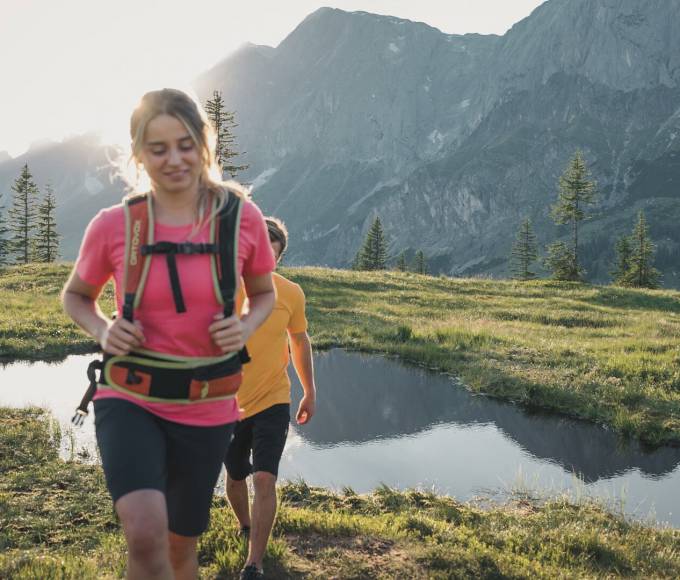 Paar beim wandern in den Bergen auf Almwiesen bei Sonnenschein in der Region Hochkönig