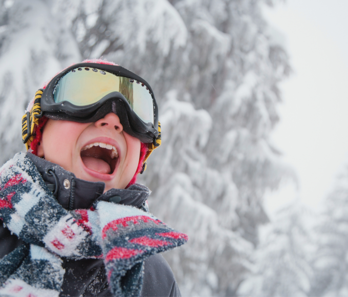 Child with ski goggles in the snow in the mountains