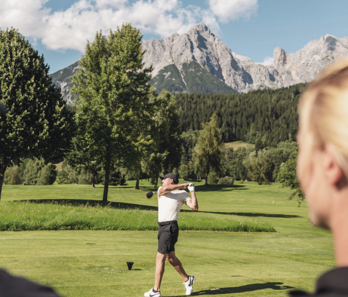 Golfer beim Abschlag am Golfplatz mit Blick auf die Berge