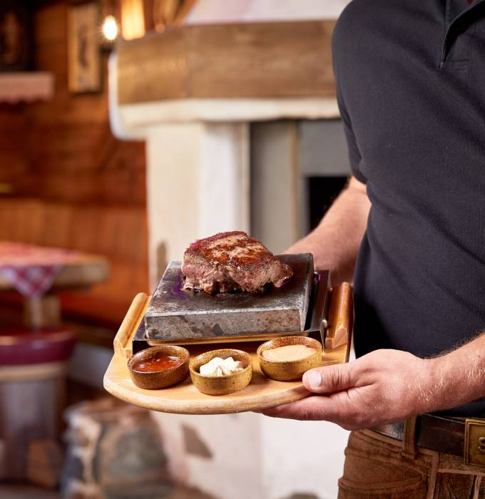Kellner zeigt Steak mit Saucenvariation