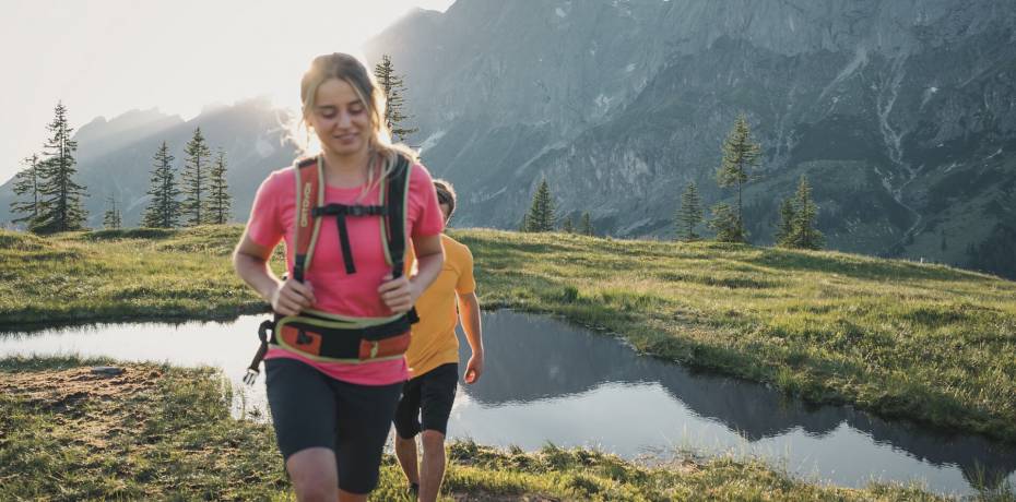 Paar beim wandern in den Bergen auf Almwiesen bei Sonnenschein in der Region Hochkönig