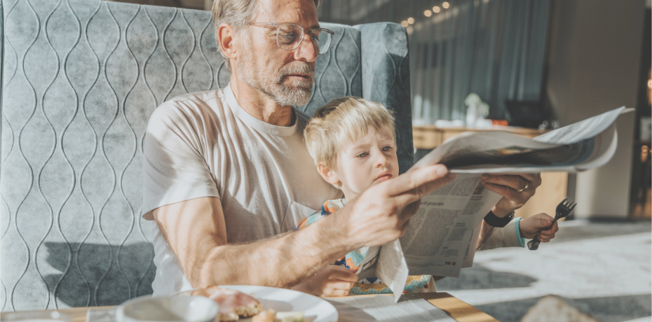 Vater und Sohn beim Frühstücken im Hotelrestaurant mit einer Zeitung