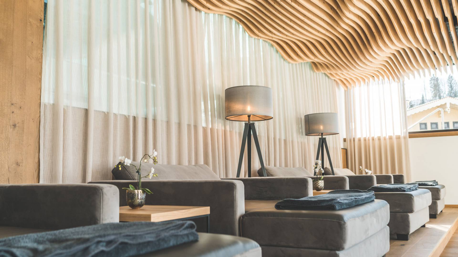 Relax area in the SPA with wavy wooden ceiling and comfortable upholstered loungers in modern design Wellnesshotel die Hochkönigin