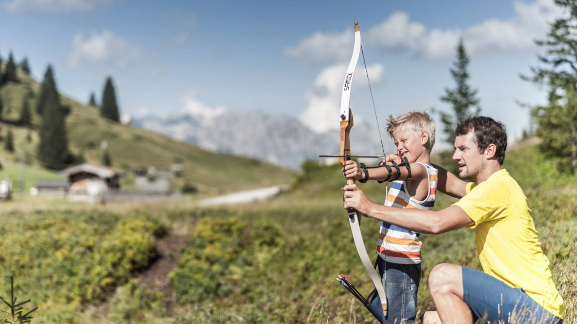 Vater zeigt Sohn wie Bogenschiessen geht in der Natur