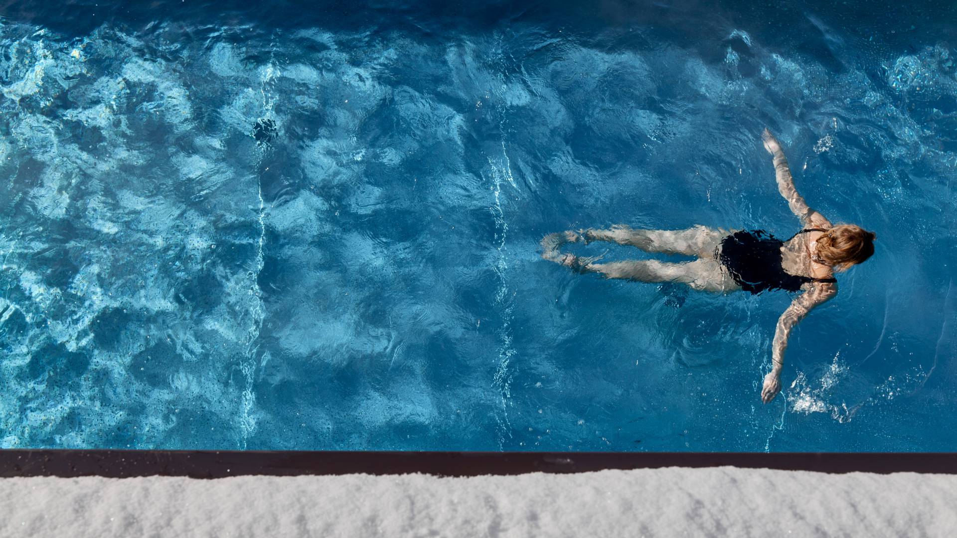 Luftaufnahme Person schwimmt im beheizten Außenpool im Winter