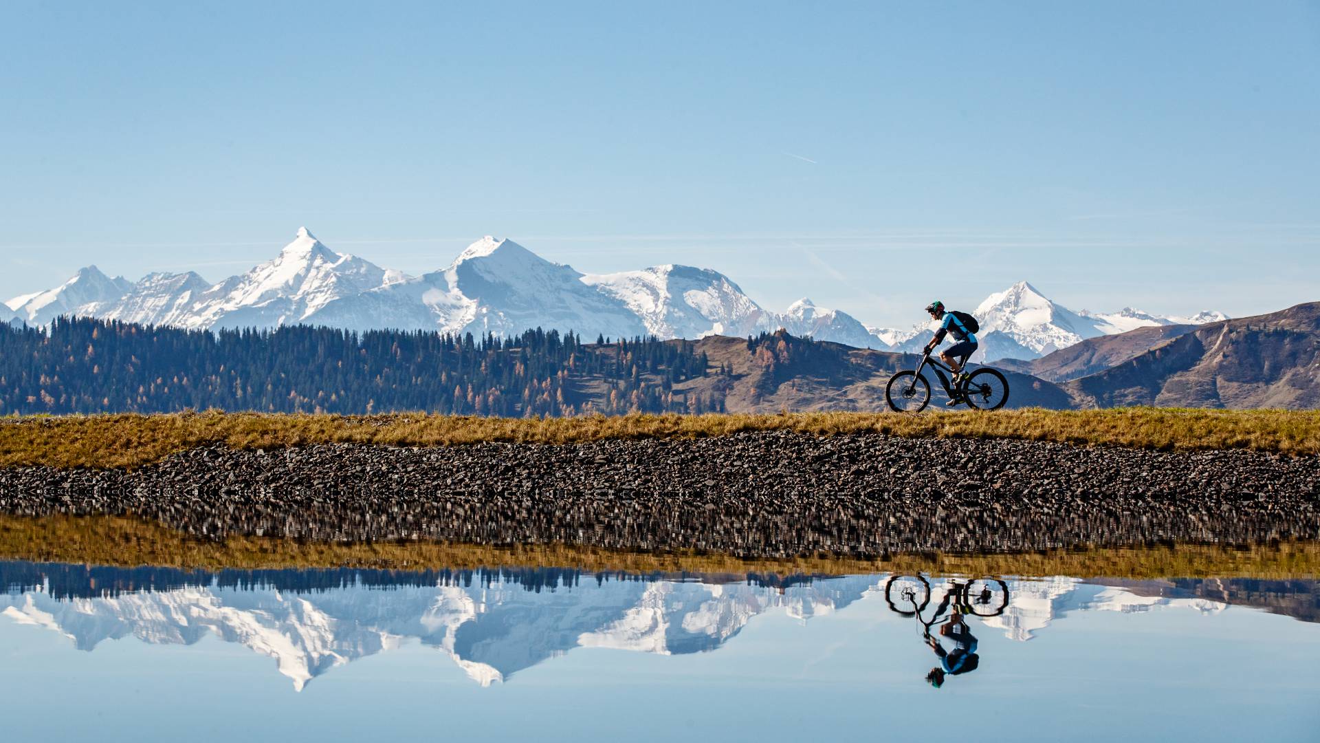 Radfahrer spiegelt sich im See mit Berglandschaft