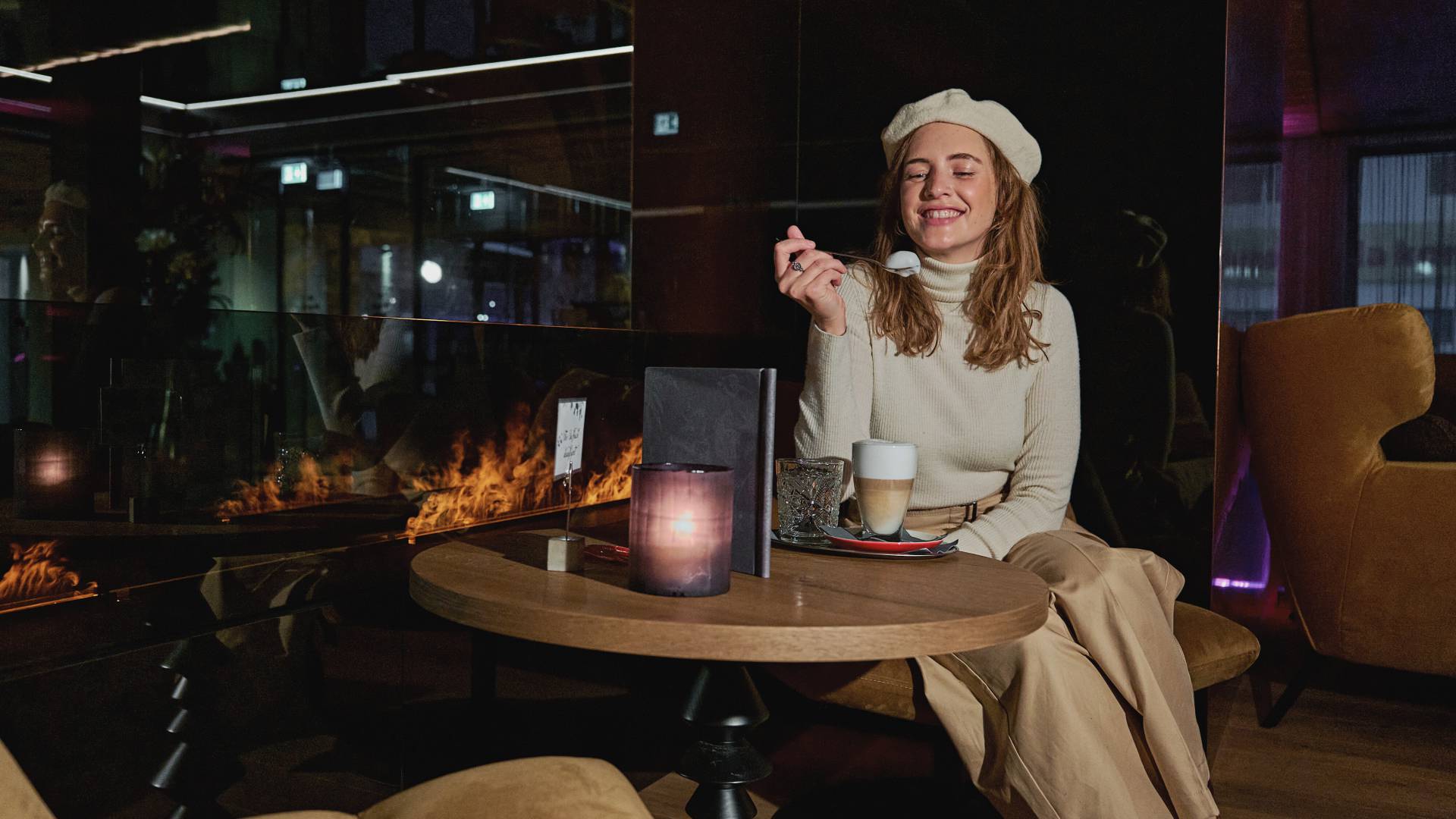 Frau in der Lounge am Kamin der HOCHKÖNIGIN mit einem Cafe Latte