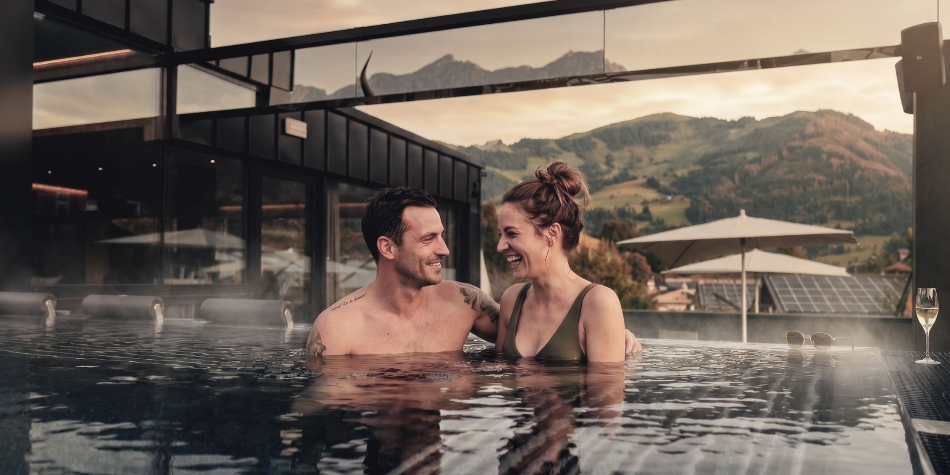 Couple relaxing in the infinity pool of the TIARA SPA adults-only area with mountain views at the HOCHKÖNIGIN wellness hotel in Maria Alm, Hochkönig.
